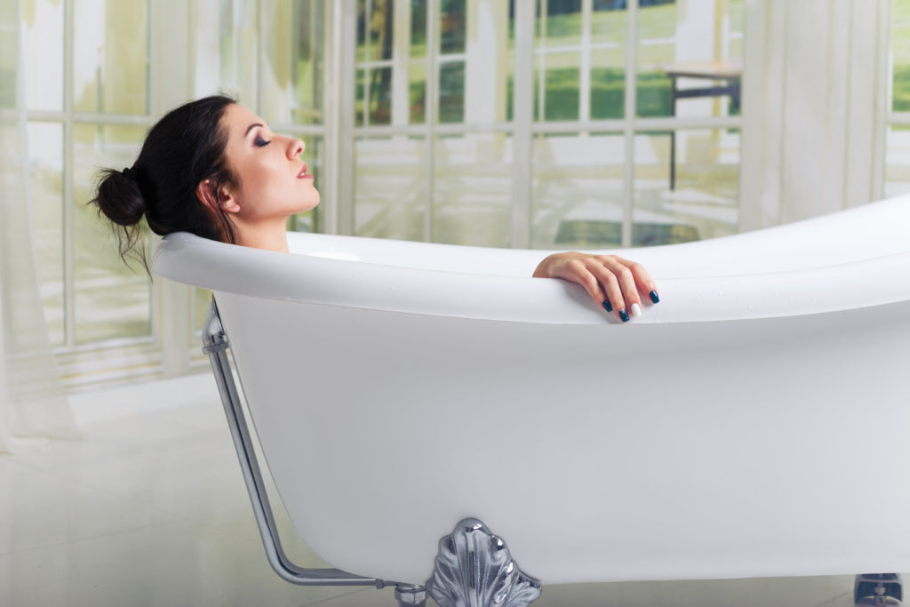 Bathing woman relaxing in bath smiling relaxing with eyes closed